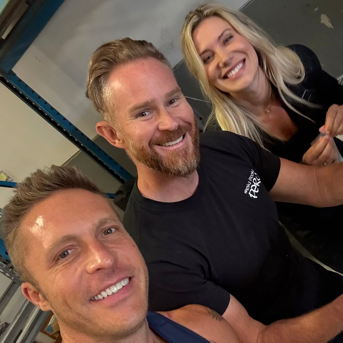 Three people taking a selfie in an indoor setting with industrial elements.